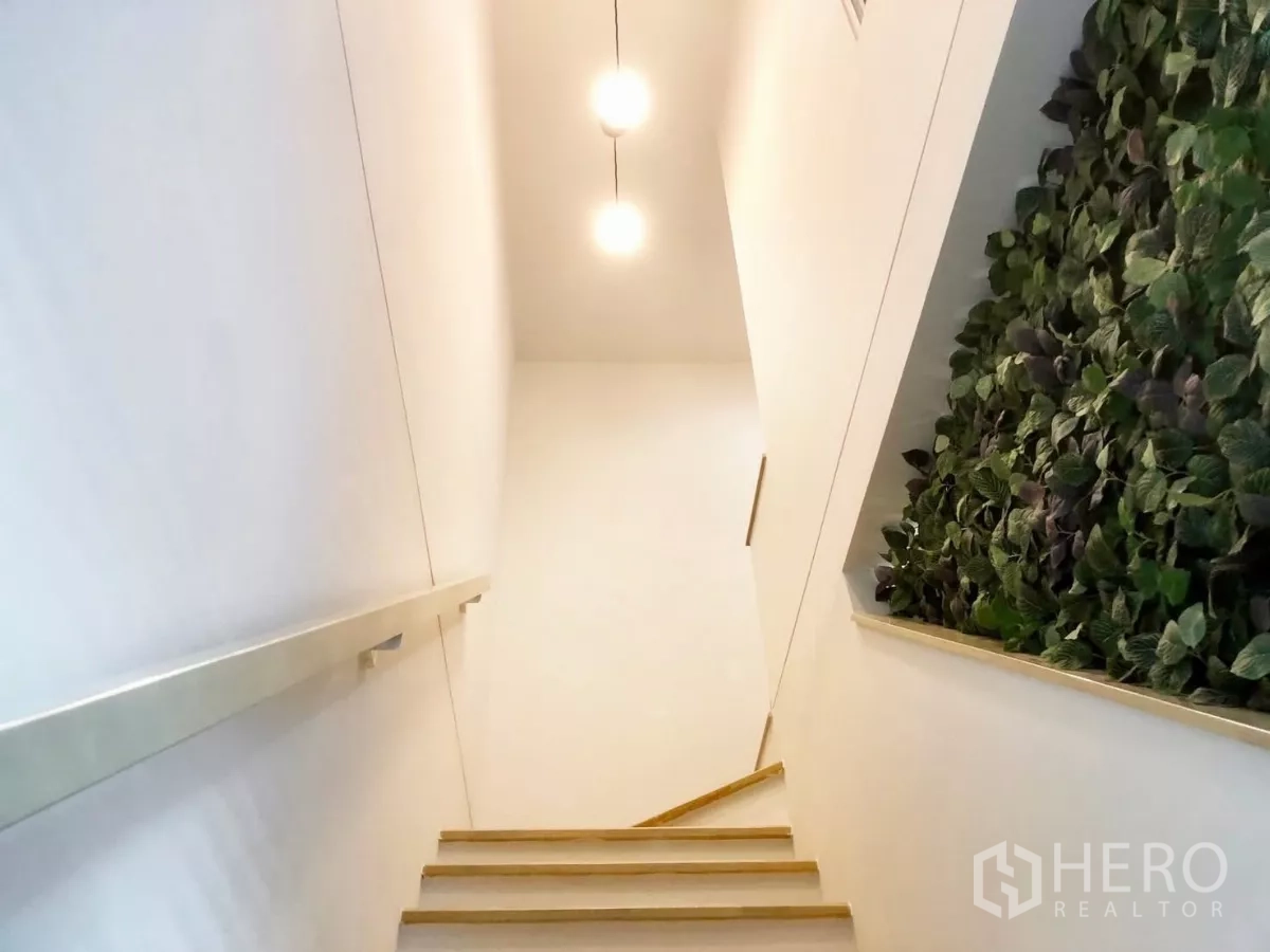 Townhouse for rent or sale in Bang Phli, Samut Prakan - Light wood staircase with pendant lights and vertical garden feature wall.