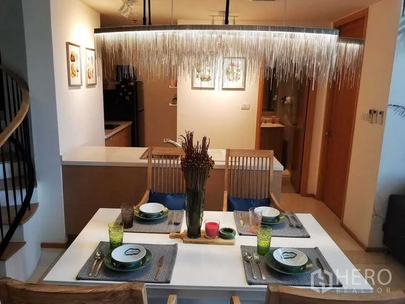 Condominium for sale in Sathon, Bangkok - Dining table set for four facing the open kitchen and a spiral staircase.