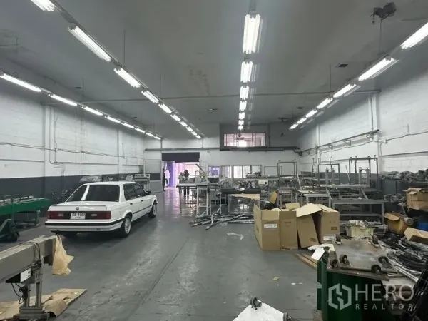 Factory for rent or sale in Khlong Luang, Pathum Thani - Workshop interior showing machinery lines, storage racks and mezzanine office window.