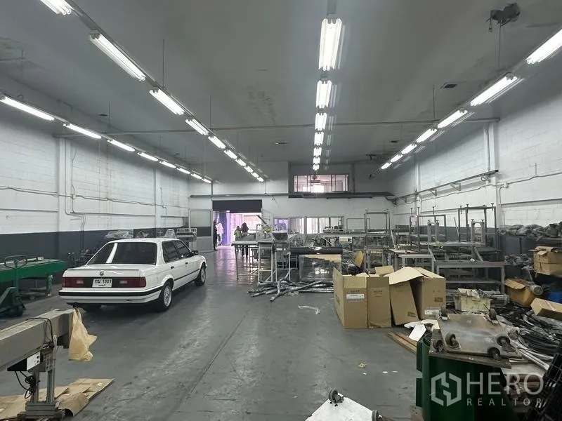 Factory for rent or sale in Khlong Luang, Pathum Thani - Workshop interior showing machinery lines, storage racks and mezzanine office window.