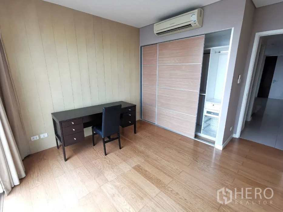 Condominium for rent in Watthana, Bangkok - Third bedroom or study with work desk, sliding closet, air conditioning, wood floors, and natural light.