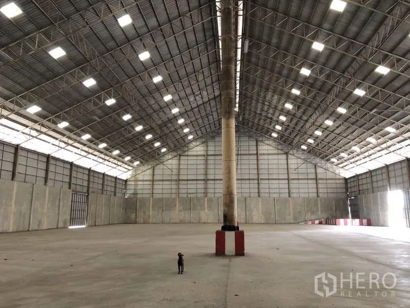 货栈 出租在Phra Nakhon Si Ayutthaya - 仓库内部对称视角，高大中央立柱、金属屋架与充足自然采光