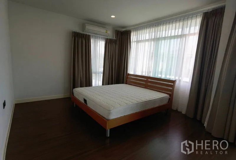 บ้าน ให้เช่าในBang Kapi, Bangkok - ห้องนอนหลักหน้าต่างกว้าง ผ้าม่าน เตียงไม้ และพื้นลามิเนตลายไม้