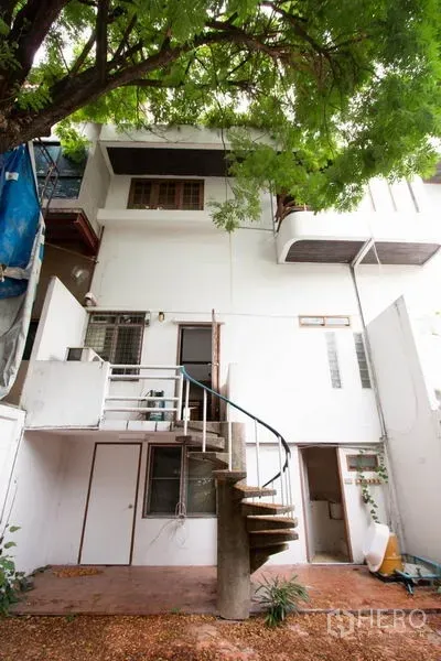 Townhouse for rent in Khlong Toei, Bangkok - Rear exterior of a white Thong Lo area townhouse with a spiral staircase beneath a shady tree.
