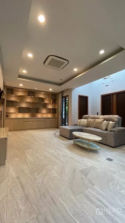 Detached House for rent in Prawet, Bangkok - Bright living room with illuminated built-in shelving, recessed lights and a sofa.