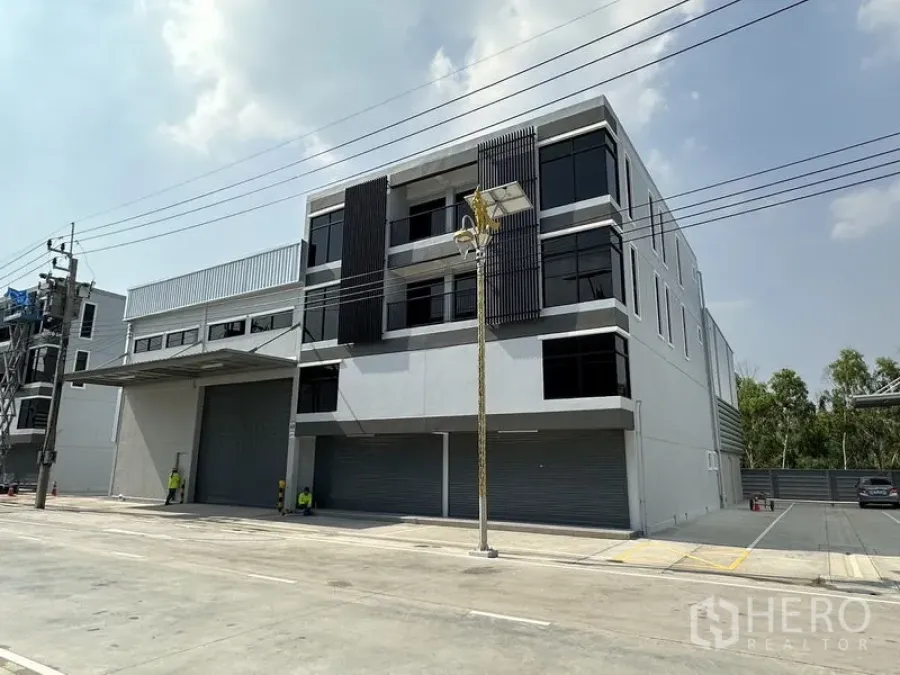 คลังสินค้า ให้เช่าในBang Phli, Samut Prakan - อาคารโกดังสมัยใหม่สูง 3 ชั้น หน้าต่างกระจกสีเข้มและประตูม้วนหลายชุด