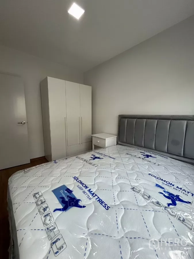 Townhouse for rent in Bang Phli, Samut Prakan - Bedroom with white wardrobe and bedside table by the window.