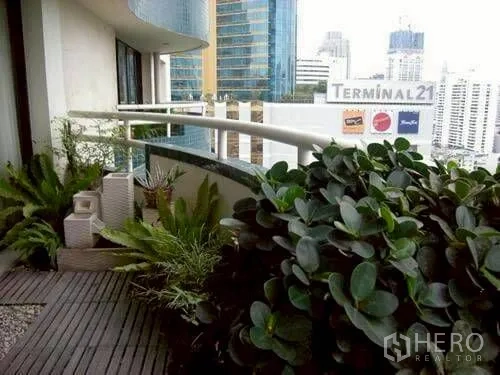 公寓 for rent or sale in Watthana, Bangkok - 阳台摆放绿植，俯瞰城市景观与 Terminal 21 标志。