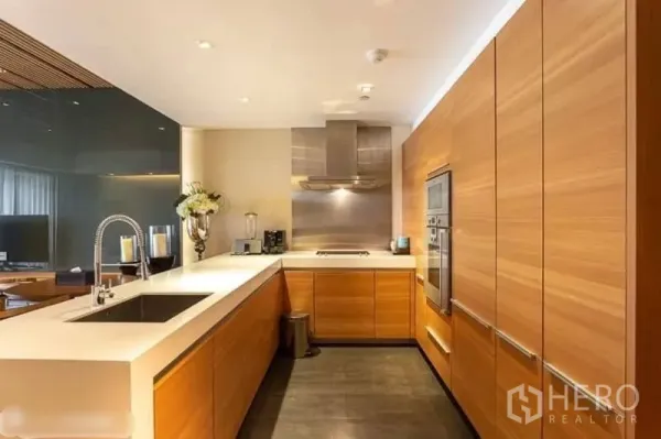 Condominium for rent in Yan Nawa, Bangkok - U‑shaped gourmet kitchen with built‑in oven, stainless range hood, and spacious solid‑surface countertops.