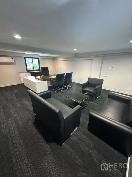 Home Office for rent - Executive office suite with desk and black leather seating set on dark carpet.