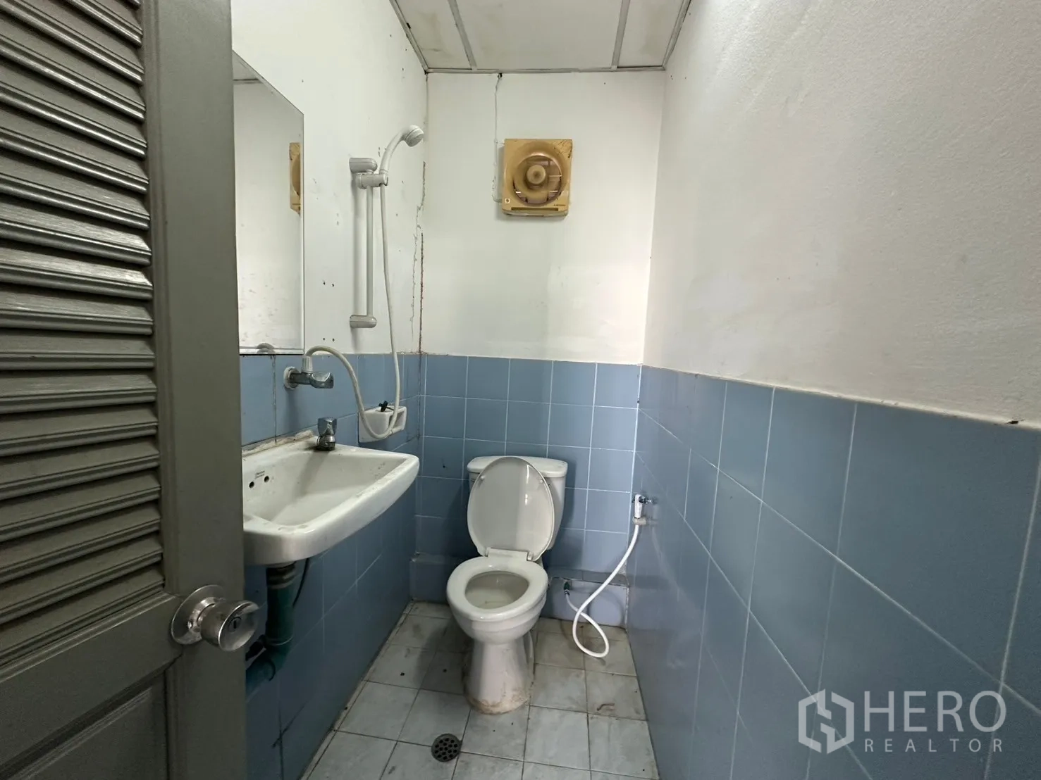 Warehouse for rent in Suan Luang, Bangkok - Restroom with toilet, sink and handheld bidet in blue-and-white tiles.