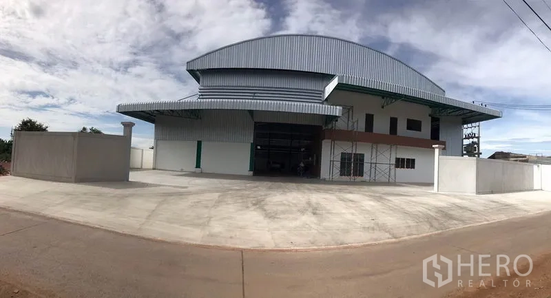 工厂 出租或出售在Mueang Samut Sakhon, Samut Sakhon - 厂区正面全景，大片混凝土硬地与围墙。