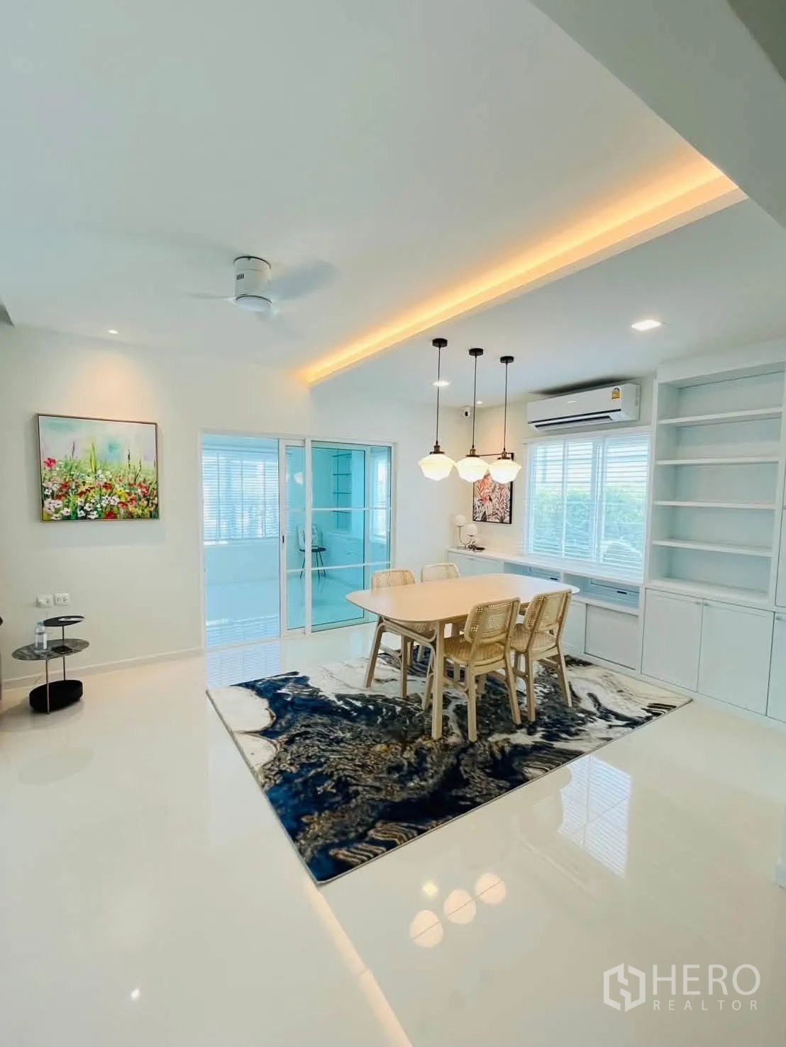 Detached House for rent in Bang Phli, Samut Prakan - Dining area with pendant lights, rug, and sliding glass doors to a glassed-in room.