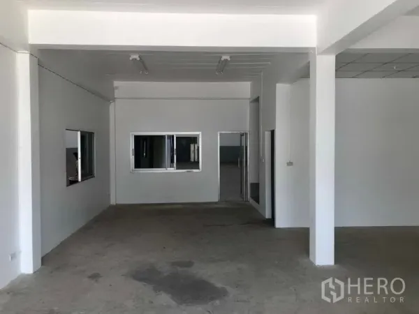 Factory for rent in Khlong Luang, Pathum Thani - Ground-floor reception or office area with white walls, windows, and a concrete floor inside the factory.