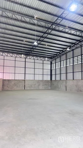 货栈 出租在Khlong Sam Wa, Bangkok - 通透无柱的仓库空间，钢梁屋顶与吊灯照明。