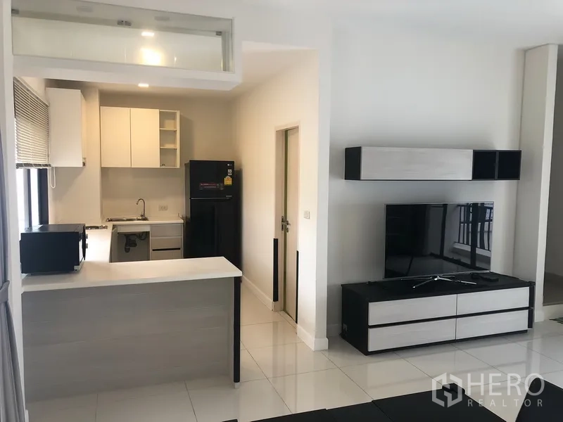 Townhouse for rent in Saphan Sung, Bangkok - Compact kitchen with breakfast counter, cabinetry, window and adjacent TV console.