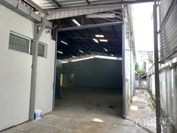 Warehouse for rent in Chatuchak, Bangkok - Wide entrance leading into a deep storage hall with concrete floor and skylights.