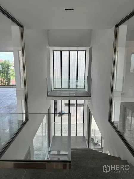 สำนักงานที่บ้าน ให้เช่าหรือขาย - มุมมองลงสู่โถงบันไดกลางอาคาร พร้อมหน้าต่างแนวตั้งสูงและราวกันตกกระจก