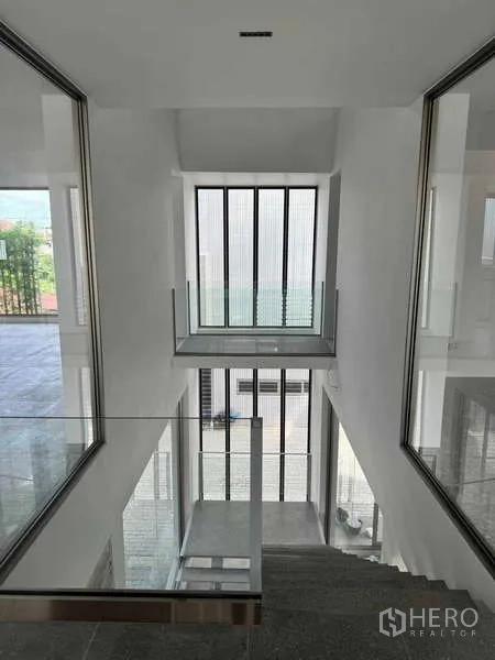 สำนักงานที่บ้าน ให้เช่าหรือขาย - มุมมองลงสู่โถงบันไดกลางอาคาร พร้อมหน้าต่างแนวตั้งสูงและราวกันตกกระจก