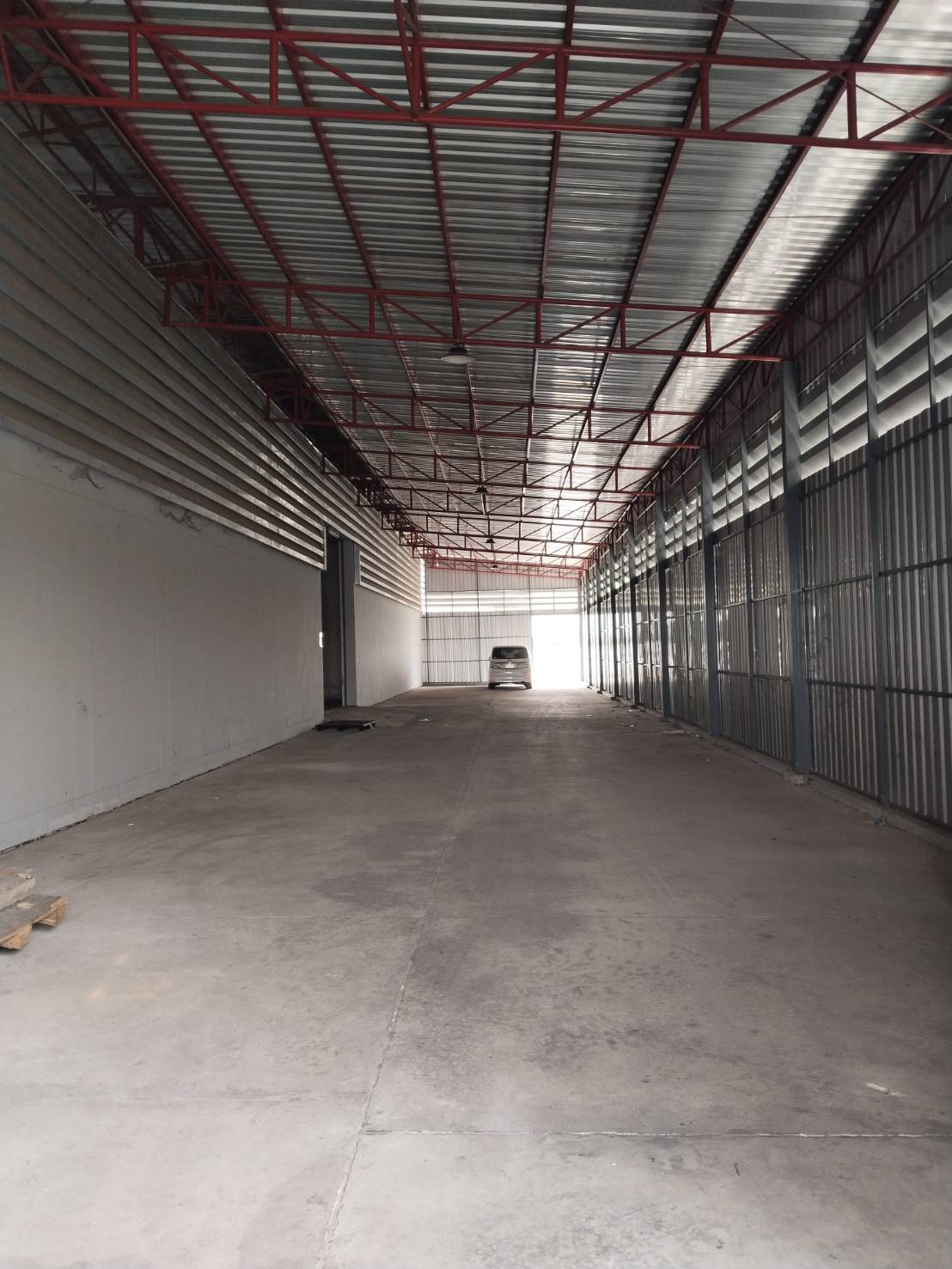 Warehouse for rent in Lat Krabang, Bangkok - Wide drive-through aisle with metal cladding and roof trusses leading to loading gates.