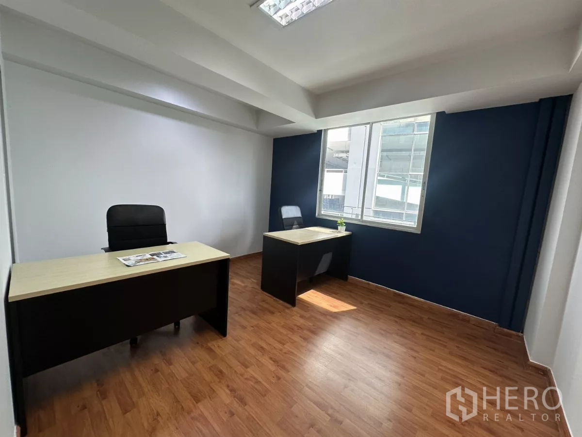 Office Space for rent in Watthana, Bangkok - Bright manager’s room with two executive desks, large window and a blue accent wall.