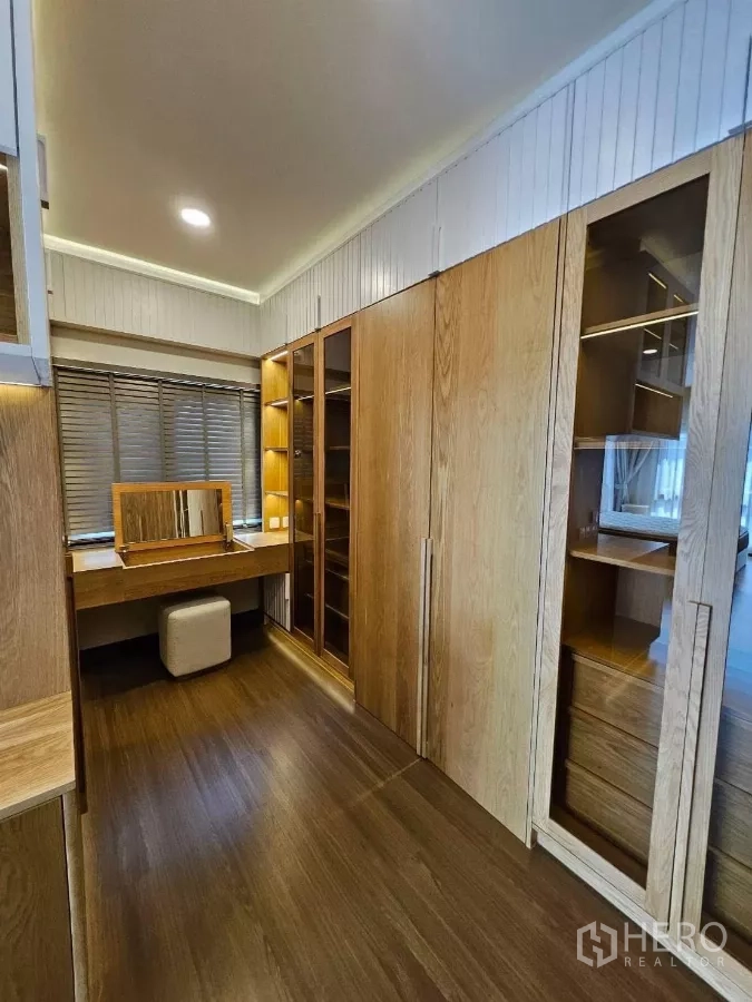 Detached House for rent or sale in Bang Phli, Samut Prakan - Walk‑in closet fitted with custom wooden wardrobes, illuminated shelving, and a dressing table with stool.