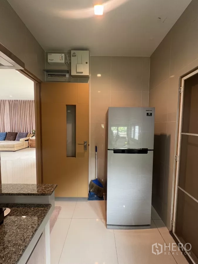 Detached House for rent in Bang Kapi, Bangkok - Kitchen entrance with refrigerator and tiled walls opening to living room.