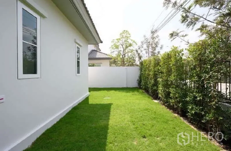 Detached House for rent or sale in Bang Phli, Samut Prakan - Side garden strip with grass and privacy hedge beside the boundary wall.