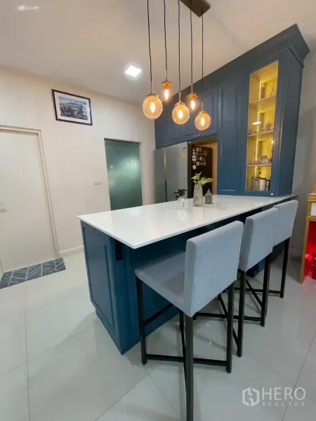 Detached House for sale in Bang Phli, Samut Prakan - Kitchen island from another angle with three bar stools and warm pendant lights.