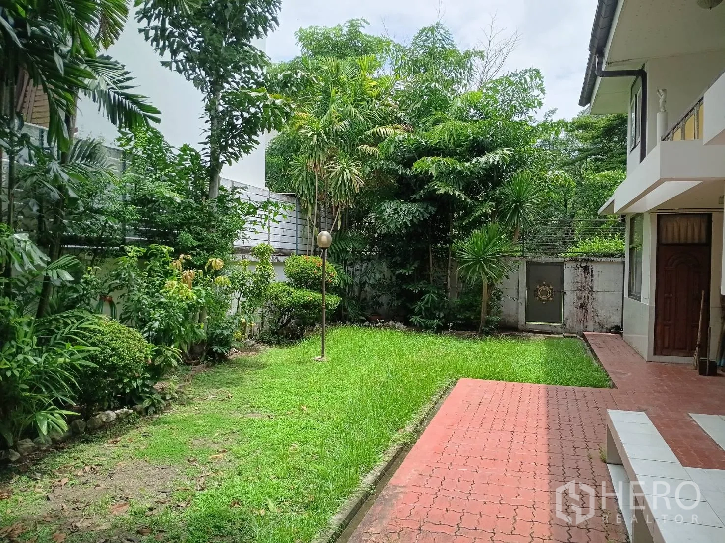 Detached House for sale in Watthana, Bangkok - Side garden with grass, a brick walkway, and a gate beside the house.