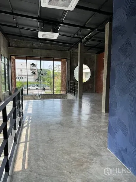 独立商业地产 出租在Sathon, Bangkok - 阁楼风格楼层，抛光水泥地、裸露黑色天花、圆形窗与落地玻璃面向街景。