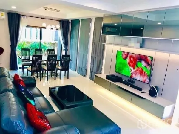 Detached House for sale in Suan Luang, Bangkok - Open‑plan living and dining area with large TV wall, sofa set, and full‑height windows.