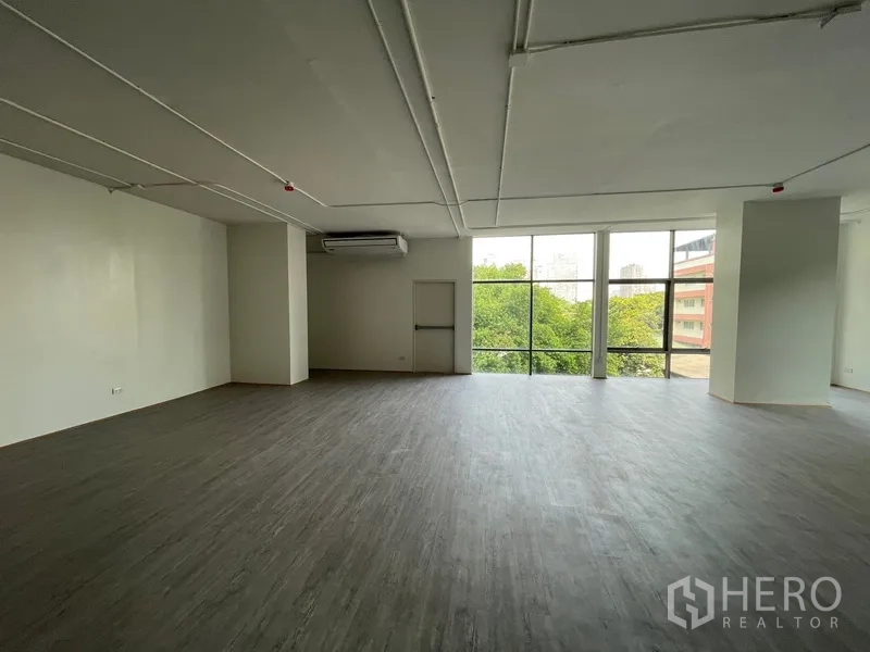 Office Space for rent in Bang Rak, Bangkok - Spacious workspace featuring a large glazed wall, vinyl floors and a central column.