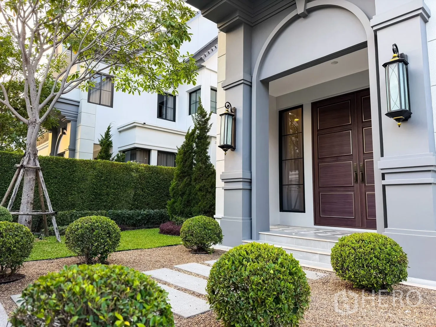 บ้านเดี่ยว for rent in Bang Khen, Bangkok - สวนหน้าบ้านตกแต่งพุ่มไม้ ซุ้มเฉลียงโค้ง และโคมไฟติดผนัง.