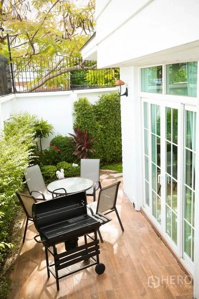 Detached House for rent in Bang Na, Bangkok - Private patio with BBQ grill, round table and chairs set amid lush hedges and greenery.