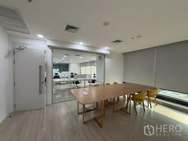 办公空间 出租在Din Daeng, Bangkok - 带木质桌和黄色椅子的会议室，通过玻璃隔断可见开放式办公区。