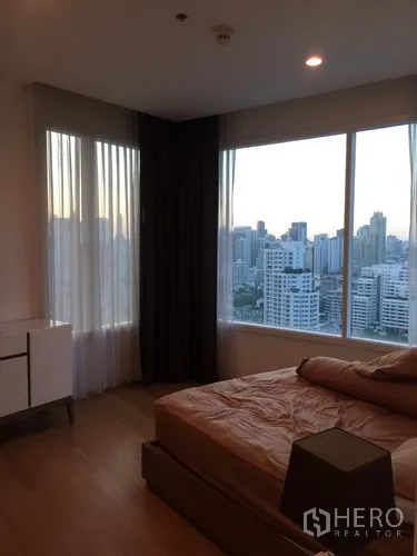 Condominium for rent in Watthana, Bangkok - Master bedroom with double bed, wide windows and sweeping skyline vistas.