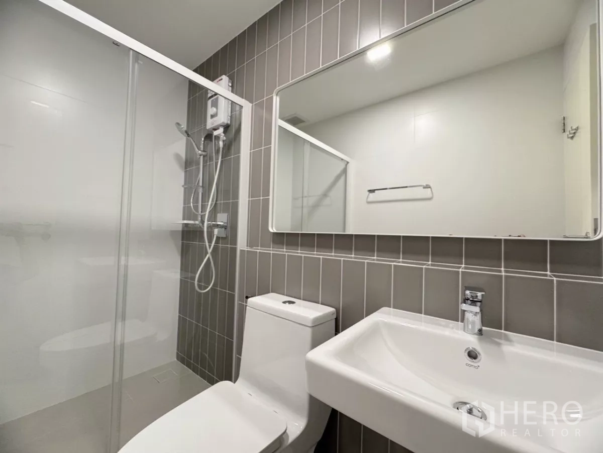 联排别墅 出租在Prawet, Bangkok - 第二卫生间设玻璃淋浴隔断与深灰墙砖。