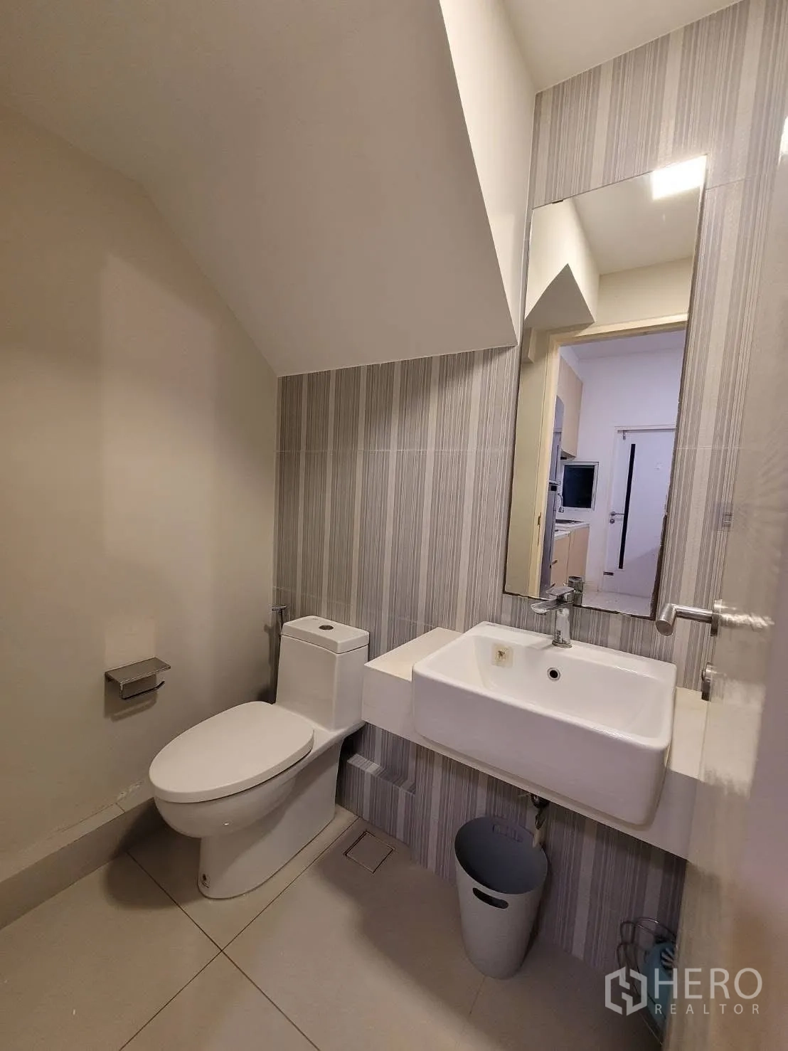 联排别墅 出租在Prawet, Bangkok - 楼梯下的客用卫生间，条纹墙砖与方形洗手盆。