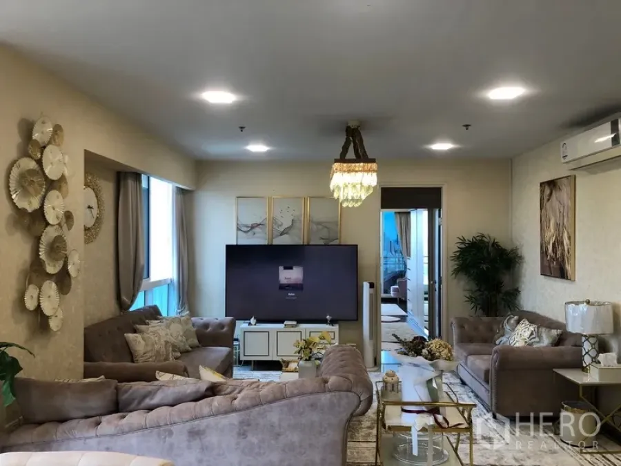 公寓 出售在Yan Nawa, Bangkok - 宽敞起居室，多组沙发、墙面装饰与大电视，灯光充足。