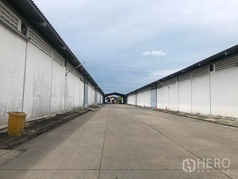 货栈 出租在Bang Pa-in, Phra Nakhon Si Ayutthaya - 两排仓库之间的宽阔混凝土车道，配有上方电线。