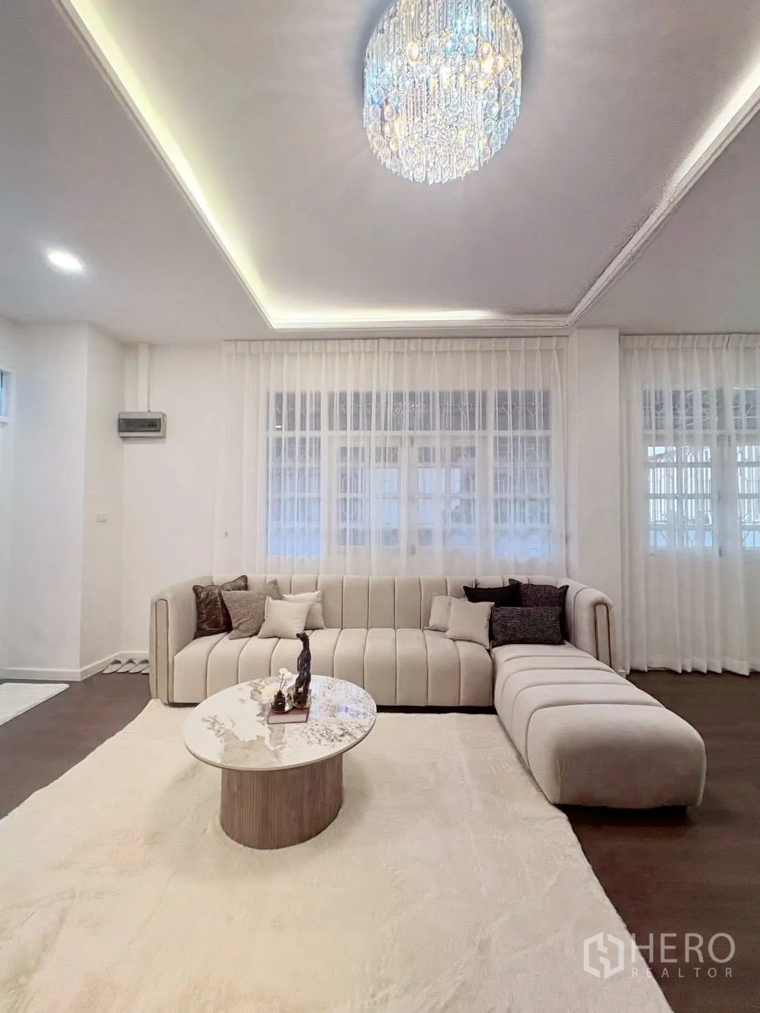 联排别墅 for rent in Huai Khwang, Bangkok - 客厅配大型L型沙发、圆形茶几与水晶灯。