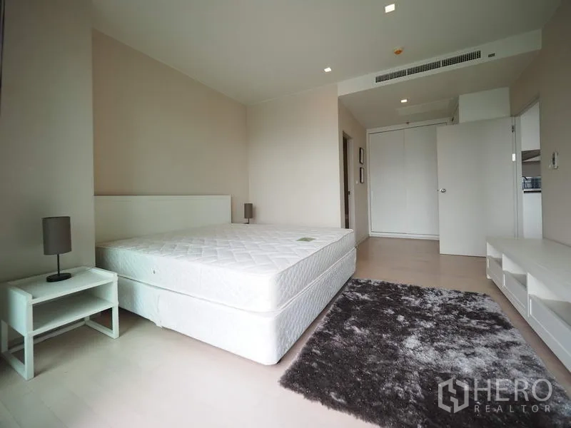 คอนโด ให้เช่าในWatthana, Bangkok - ห้องนอนกว้าง มีตู้เสื้อผ้าบิลท์อิน โต๊ะข้างเตียง และพรมโทนอุ่นในคอนโดสไตล์โมเดิร์น