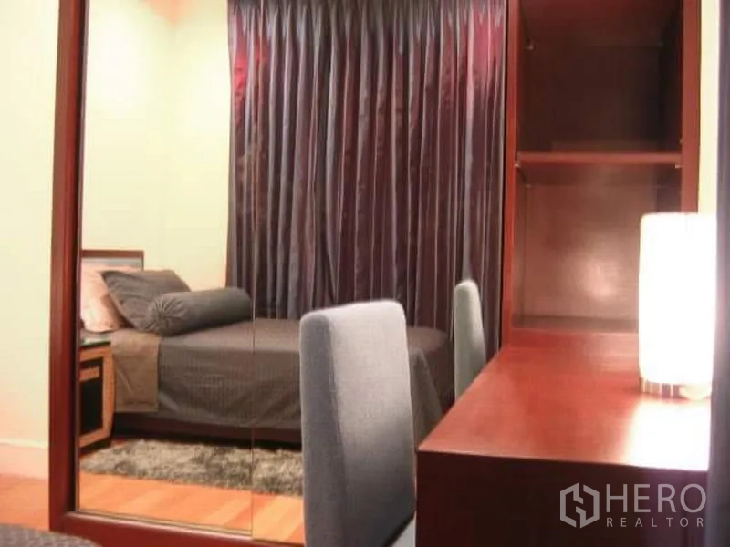 คอนโด ขายในKhlong Toei, Bangkok - ห้องนอนรอง พร้อมโต๊ะทำงาน ตู้เสื้อผ้ากระจก ผ้าม่านสีเข้ม และแสงไฟนุ่ม