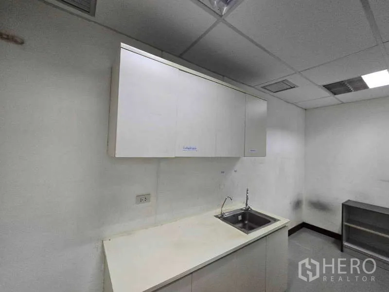 Office Space for rent in Khlong Toei, Bangkok - Compact office pantry with sink and white cabinetry.