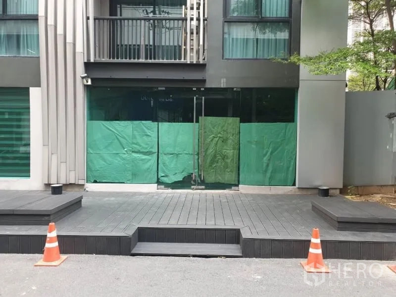 零售空间 出租在Watthana, Bangkok - 现代建筑外立面，玻璃入口与抬高木平台，适合招牌。