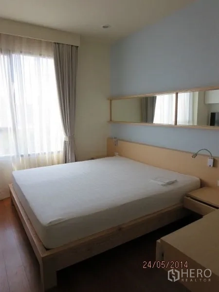 公寓 出租在Bang Rak, Bangkok - 明亮卧室，大窗、浅木床架与素雅配色。