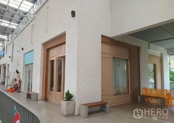 พื้นที่ขายปลีก ให้เช่าในKhlong Toei, Bangkok - อาเขตค้าปลีกสมัยใหม่ ผนังอิฐสีขาว หลังคาโปร่งแสง พร้อมหน้าร้านประตูไม้สูงและม้านั่ง