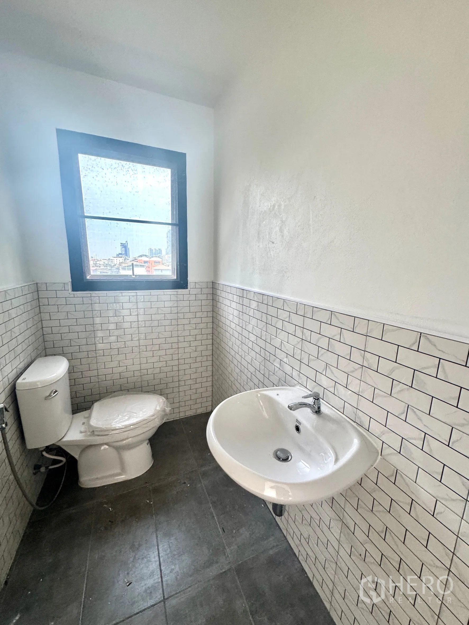 办公室 for rent in Sathon, Bangkok - 带窗卫生间，设坐便与壁挂式洗手盆，地铁砖墙面。