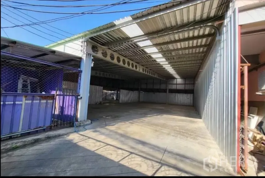 Warehouse for rent in Din Daeng, Bangkok - Covered warehouse entrance with metal roof, open bay and concrete floor.